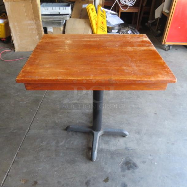 Wooden table top on a metal pedestal base, 24x30x30 inches, in used condition with visible wear and scratches.