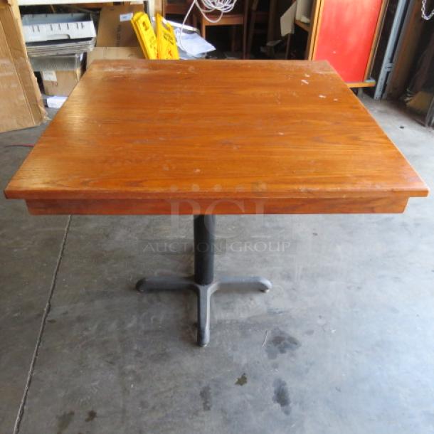 Wooden table top with pedestal base, 36x36x30 inches. Features a sturdy design with minor surface wear, ideal for dining or workspaces.