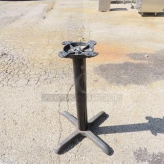 Black metal pedestal base with four mounting holes, cross-shaped feet. Slight wear visible on base. Ideal for tables or displays.