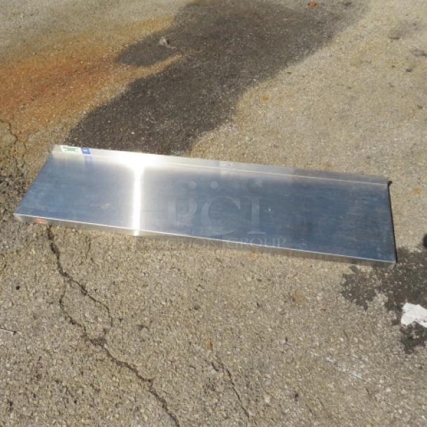 48x12 stainless steel shelf on pavement, reflective surface, good condition.