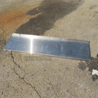 48x12 stainless steel shelf on pavement, reflective surface, good condition.