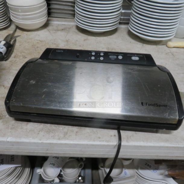FoodSaver vacuum sealer, stainless steel, minor surface wear, visible control buttons, used condition.