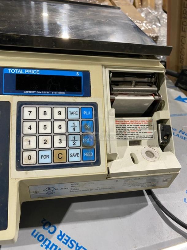 CAS-USA LP1000 digital price computing scale with label printer, stainless steel worktop, and legs. Capacity: 30 lbs, 120V.
