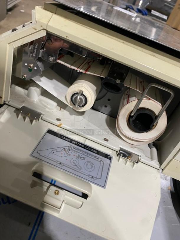 CAS-USA LP1000 digital price computing scale with open label printer, showing internal label rolls and stainless steel worktop.