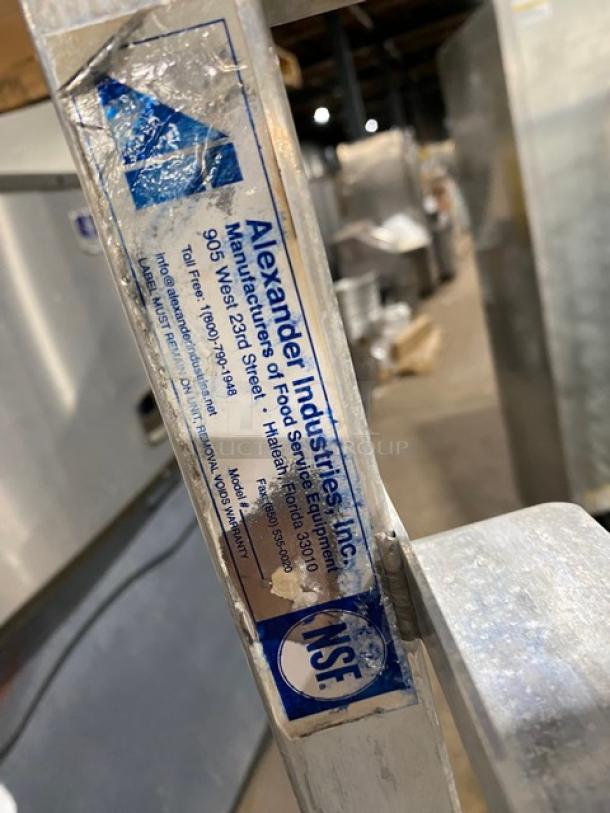 Alexander Industries heavy-duty pan rack on casters, used condition. Visible NSF label and company details indicate authenticity.