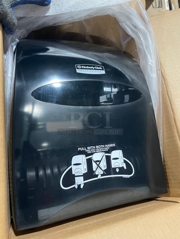 Brand new Kimberly Clark Sanitouch 09996 smoke black paper towel dispenser in box, features dual-hand pull method.