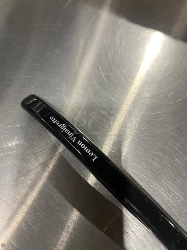 Carlisle black 9.5" lemon vinaigrette ladle, model 02955979, brand new, shown on reflective surface.