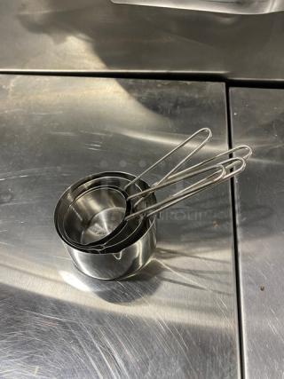 New commercial stainless steel measuring cup set, nested, with wire handles. Ideal for precise measurements.