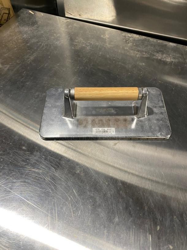 Brand new Vollrath steak weight, model 47709, cast aluminum with waffle-patterned grid, wooden grip handle, visible label.