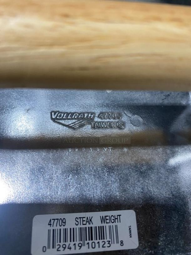Brand new Vollrath 47709 cast aluminum steak weight with waffle-patterned bottom and wooden grip. Brand and model stamped.