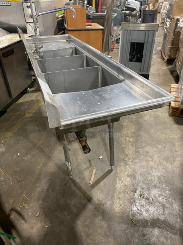 Duke Manufacturing stainless steel 3-compartment sink with left and right drain boards, backsplash, swing spout, and jet spray faucet on legs.