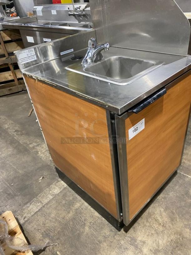 Duke Manufacturing stainless steel hand washing cabinet, model SUB-PS-24-C M, with backsplash and right-side splash, wood-paneled exterior.