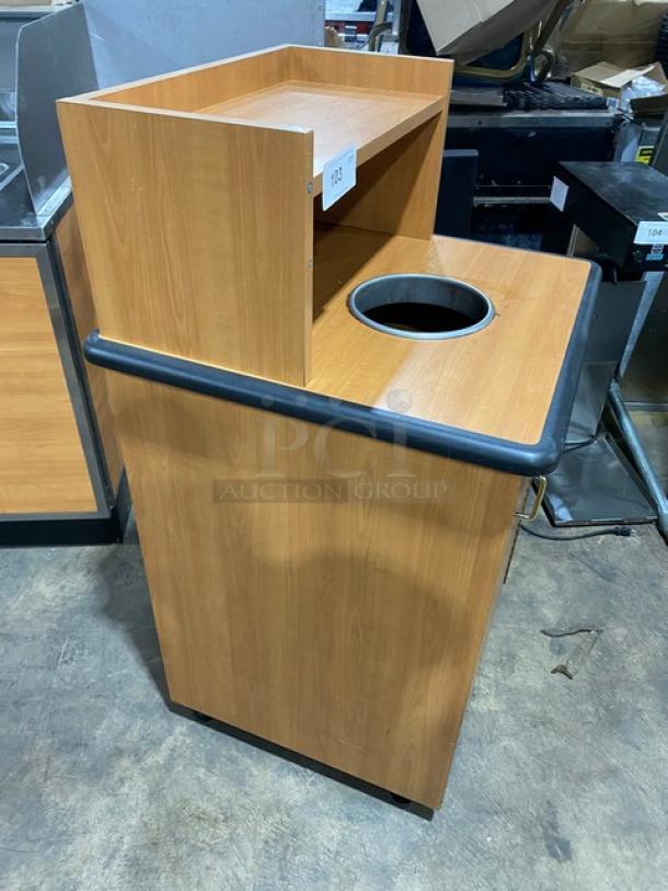 Commercial wooden recycle-style trash cabinet with upper serving tray storage, on legs. Features a round waste opening.