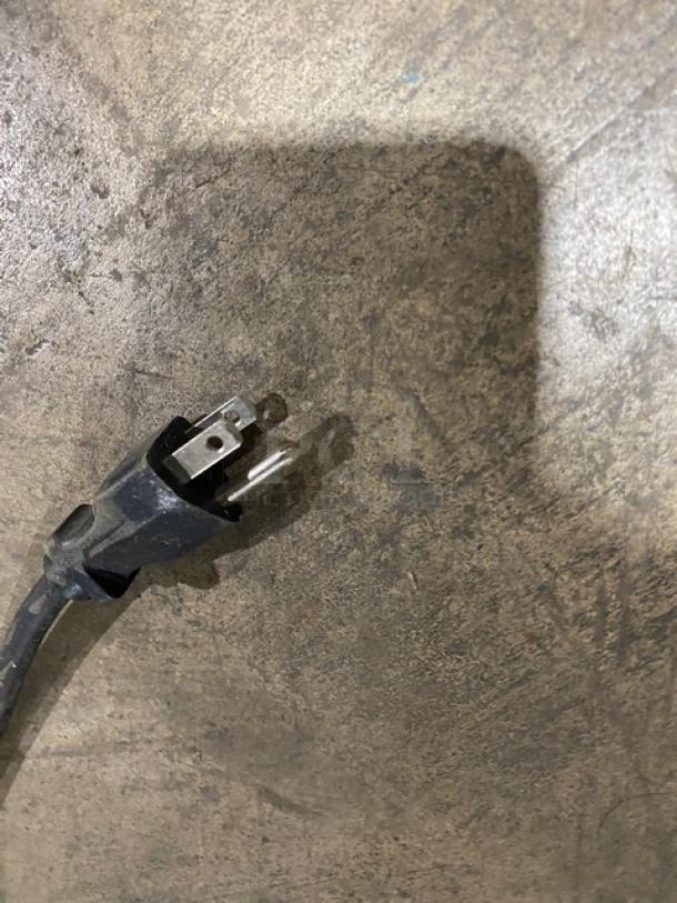 Power plug for Bunn ITCBDV commercial coffee and tea brewer, stainless steel, 120V, 1 phase, visible on concrete surface.