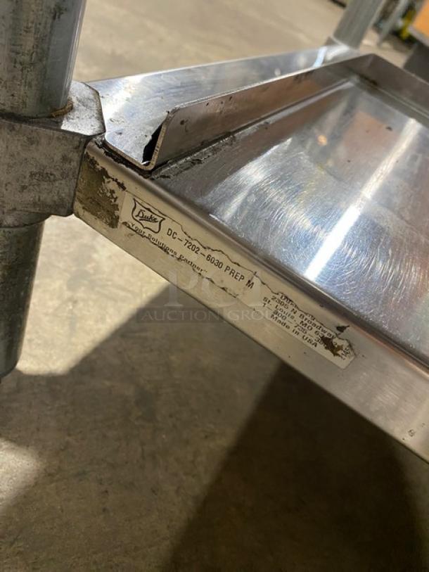 Duke Manufacturing stainless steel prep table, model DC-7202-6030, with undershelf and trash chute cut-out, on legs.