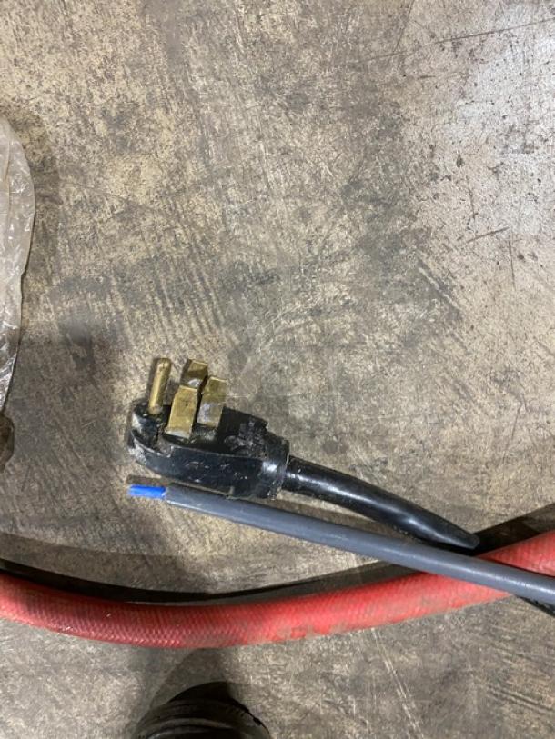 Power cord plug for Hobart LXEH dishwasher. Three-prong connector on a concrete surface.
