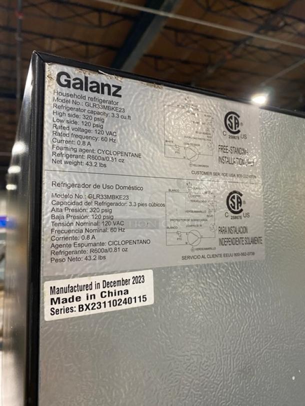 Galanz GLR33MBKE23 black mini refrigerator, 3.3 cu ft. Labels show model info, 120V, made Dec 2023 in China, SN: BX23110240115.