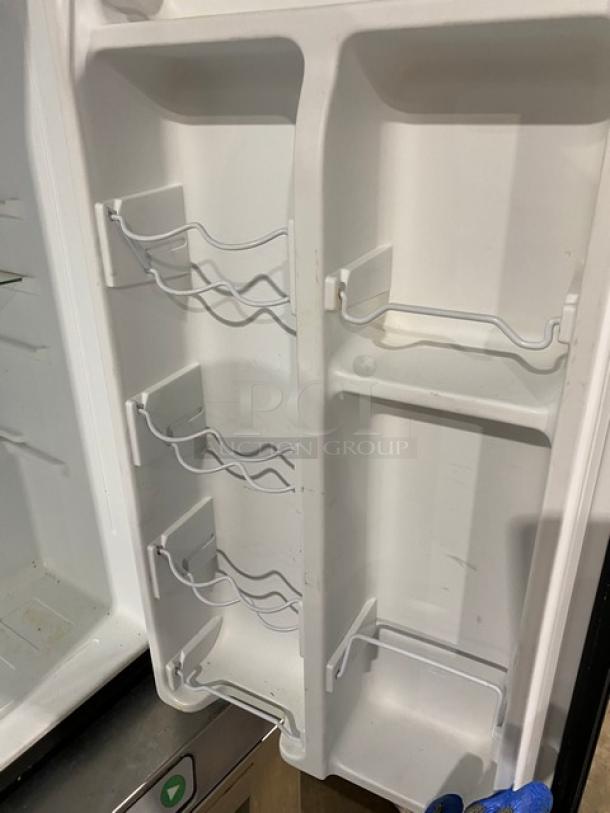 Galanz mini refrigerator door interior with multiple wire shelves and racks, Model GLR33MBKE23, in clean condition.
