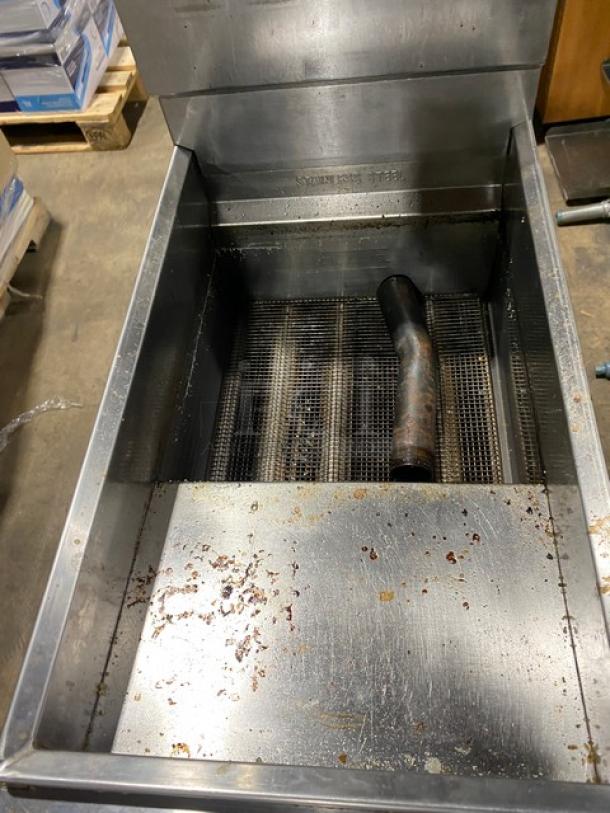 American Range commercial stainless steel deep fat fryer with back splash, basket hanger, and legs. Natural gas powered. Signs of use visible.