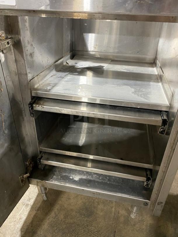 Custom commercial stainless steel work cabinet with double interior pull-out shelves. Enclosed style on sturdy legs. Visible wear.