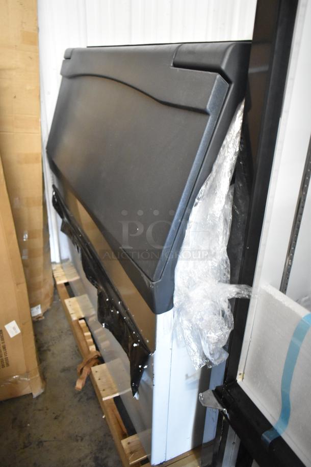 Brand new stainless steel commercial ice bin, scratch and dent condition, partially wrapped, on pallet in warehouse.