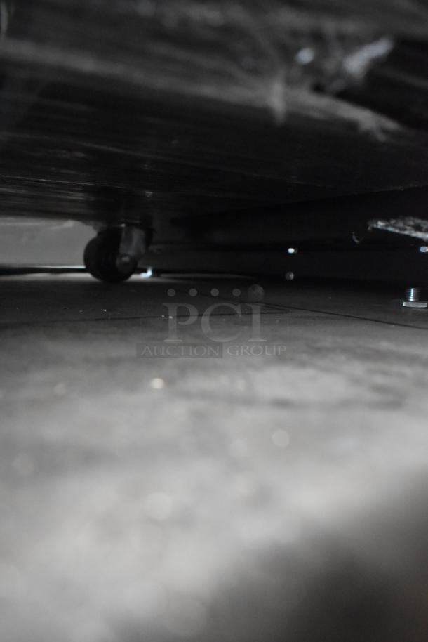 Underneath view of True T-19F reach-in freezer showing commercial caster wheel. Stainless steel, 2017 model.