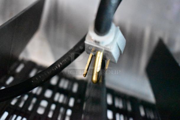 Close-up of a metal electrical plug for a True GDM-41SL-54-HC-LD commercial cooler, showing prongs and black cord.