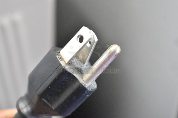 Close-up of a power plug for a Brother MFC-9440CN printer, showing the plug's metallic prongs.