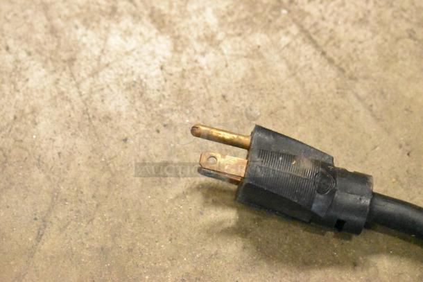 A three-prong electrical plug on a concrete surface.