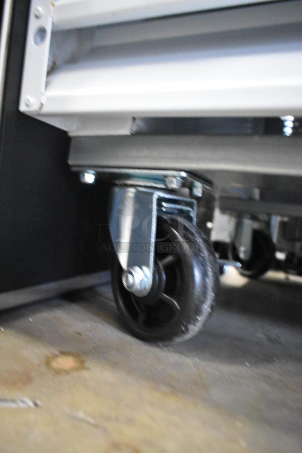 Close-up of a commercial caster wheel on the Avantco 178GDC40HCW merchandiser refrigerator, showing metal construction.