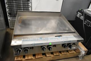 Brand new Garland stainless steel commercial flat top griddle, scratch and dent, on wooden pallet, with control knobs visible.