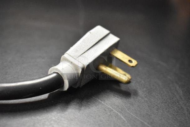 Close-up of a three-prong electrical plug connected to a black power cord, part of the True GDM-41SL-48-HC-LD cooler.