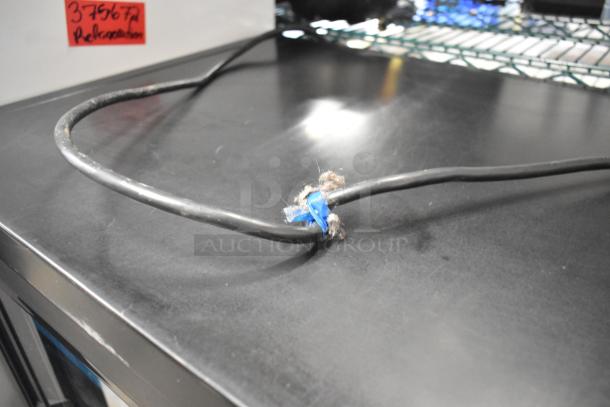 Close-up of power cord on a 2019 True GDM-41SL-48-HC-LD metal commercial cooler, showing wear and repair with blue tape.