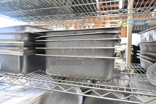 Lot of stainless steel drop-in bins, chafer lids, salad plates, and bowls on wire shelving. Shelving not included.