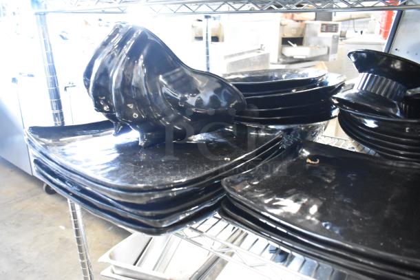 Metro lot of black salad plates and bowls stacked on a metal shelf. Includes additional kitchen items, excludes shelving unit.