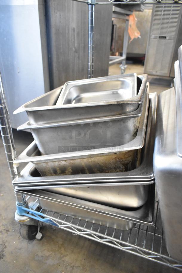 Various stainless steel drop-in bins in used condition, stacked on a wire rack. Chafer lids, salad plates, and bowls included.