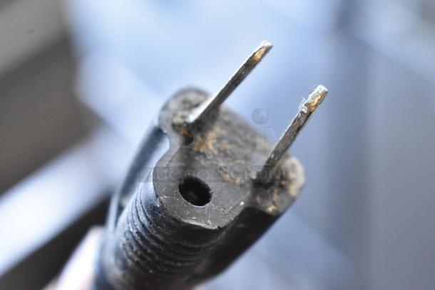 Close-up of an electrical plug for commercial countertop food warmers, emphasizing metal prongs and condition.