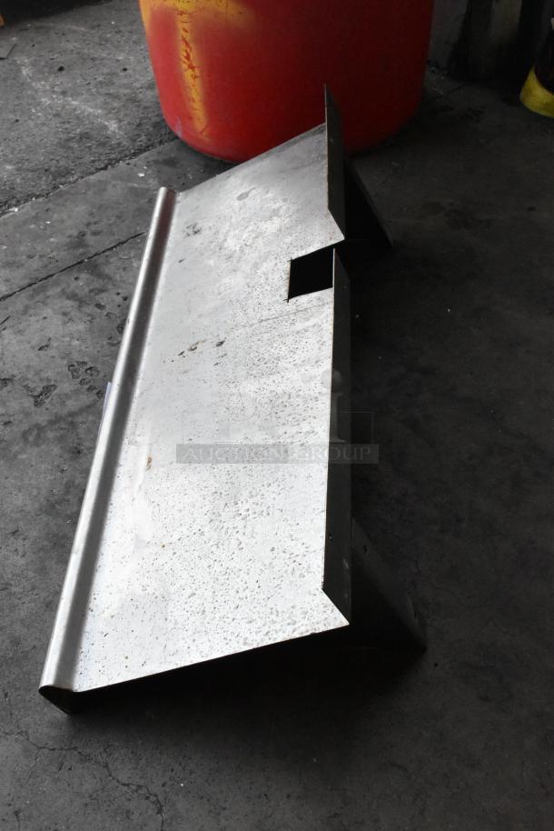 Metal wall mount shelf in used condition, featuring a simple rectangular design with mounting brackets, suitable for storage needs.