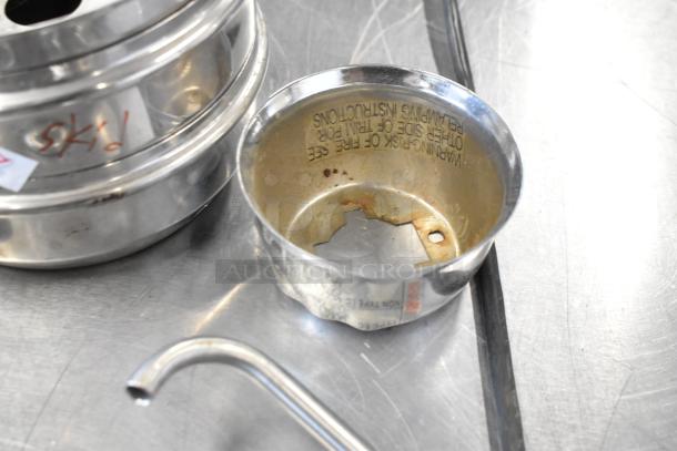 Lot of various metal items on a table, includes server pump parts. Some items show rust and wear, marked with stickers.