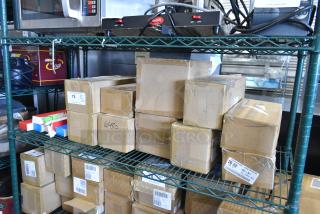 Tiered lot of various boxed items on shelving, includes Sabatier potato ricer blade and stackable egg dispensers. Labels present.