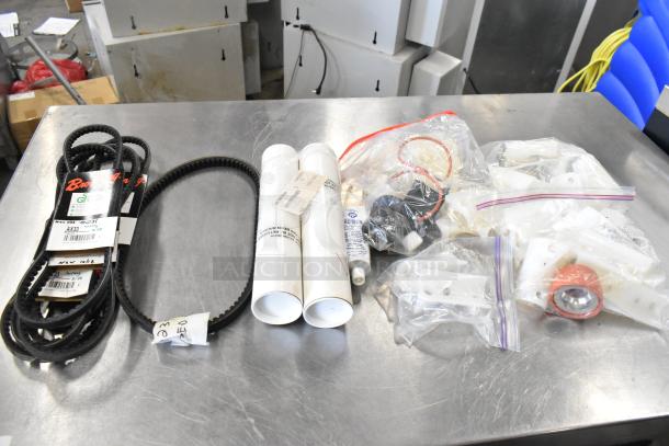 Lot of miscellaneous items including rubber belts, PVC tubes, and bagged parts on a metal table, various conditions.