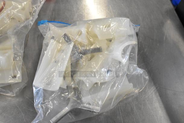 Lot of various items including plastic parts in clear bags on a metal surface. Condition appears unused.