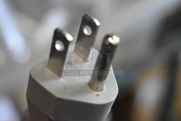 Close-up of a three-prong plug connected to the Solwave 180MW1000SS microwave oven, highlighting electrical compatibility.