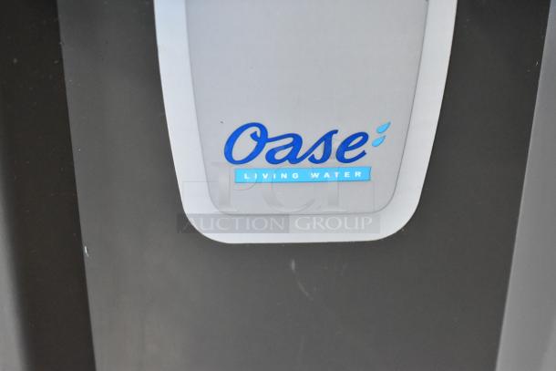 Oase Gray Bin with "Living Water" logo, subtle gray and black design, in good condition.