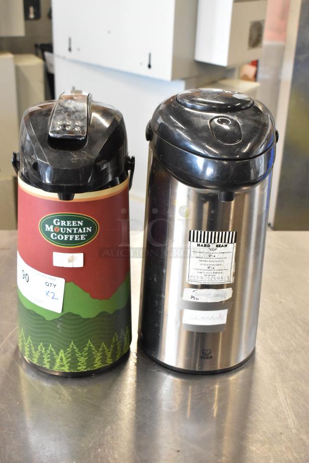 Two air pots; one branded Green Mountain Coffee with a red and green design, the other stainless steel from Tiger with visible labels.