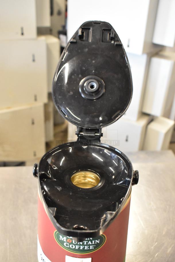 Mountain Coffee air pot with open lid, red exterior, visible spout. In good condition.