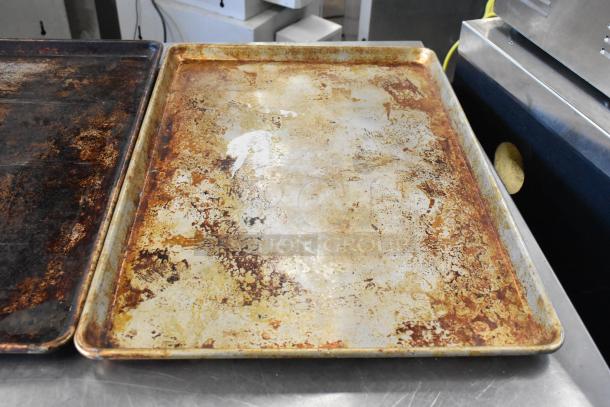 Three metal baking pans with visible wear and discoloration. Used condition. Ideal for commercial kitchen use.