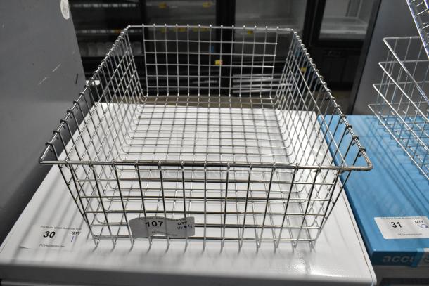 Four metal wire baskets, square shape, stainless steel, arranged on a white surface. Tags indicate auction details.