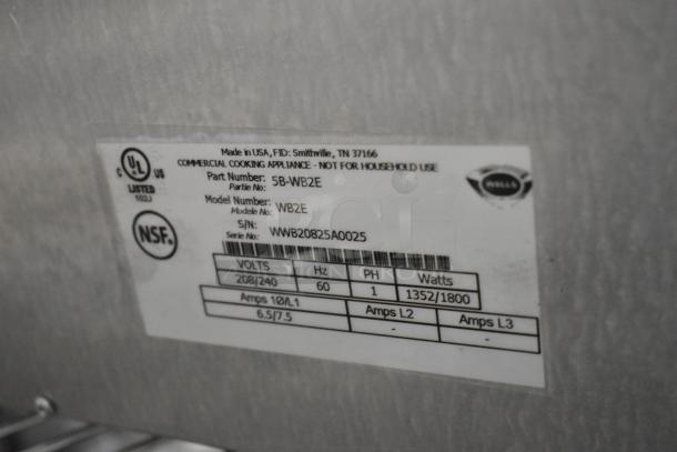 Wells WB2E metal commercial double waffle maker label, shows 208/240 volts, 1 phase, UL and NSF certified, serial number visible.