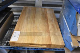 Brand new wooden cutting board, scratch and dent condition, rectangular with handle cutout, natural wood grain finish.